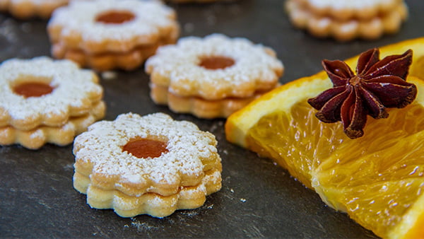 spitzbugen linzer plätzchen mit marmelade und puderzucker mit zitronenscheibe in stern bzw blumenform