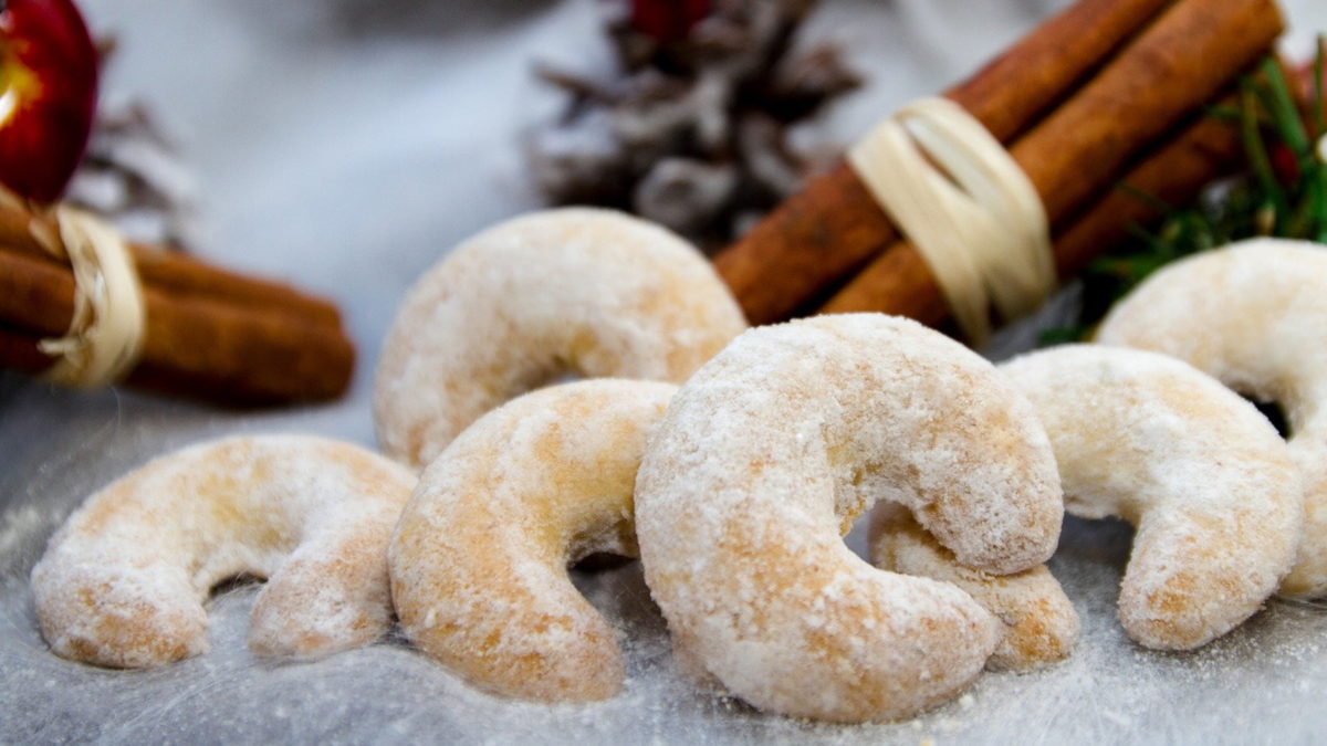 vanillekipferl mit zimtstangen und tannenzweigen als weihnachtliche dekoration