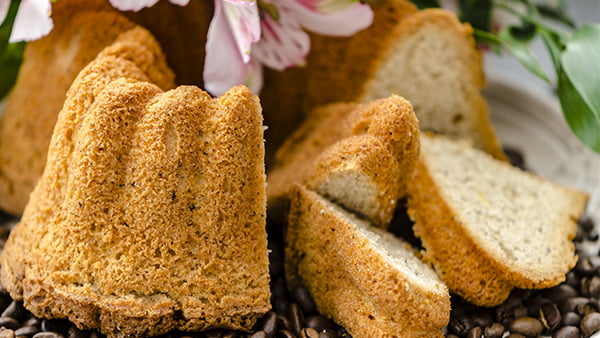 angeschnittener gugelhupfkuchen in herzform angerichtet auf kaffeebohnen