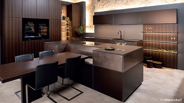 elegante warendorf küche aus dunklem holz mit edlen lichtelementen und kücheninsel mit integriertem holztisch sowie vier schwarzen stühlen