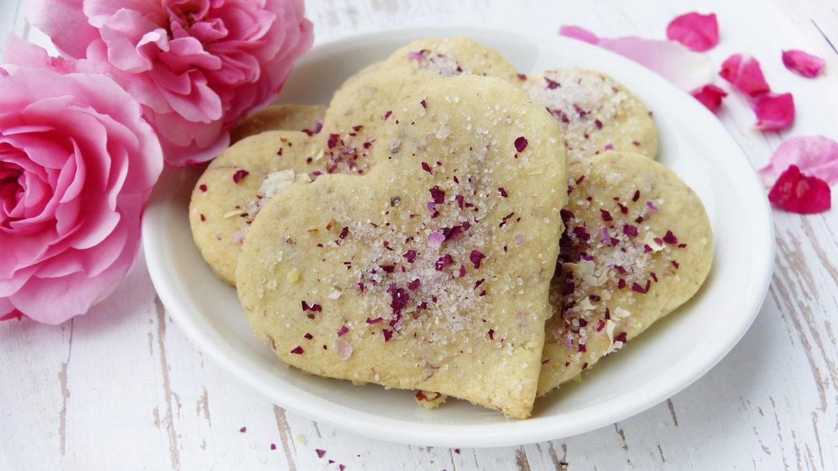 herzkekse zum valentinstag mit zucker und rosenblättern bestreut