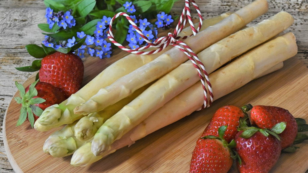 spargel mit erdbeeren auf rundem holztablett