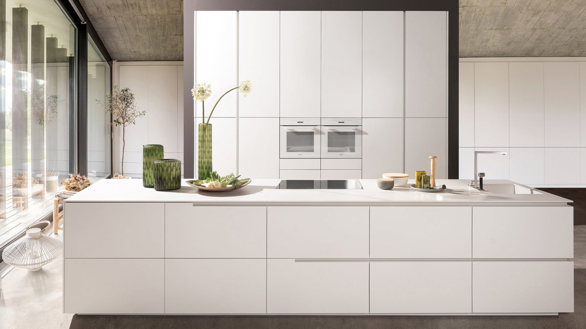 elegante weiße küche ohne griffe von warendorf mit küchenhochschrank und kochinsel