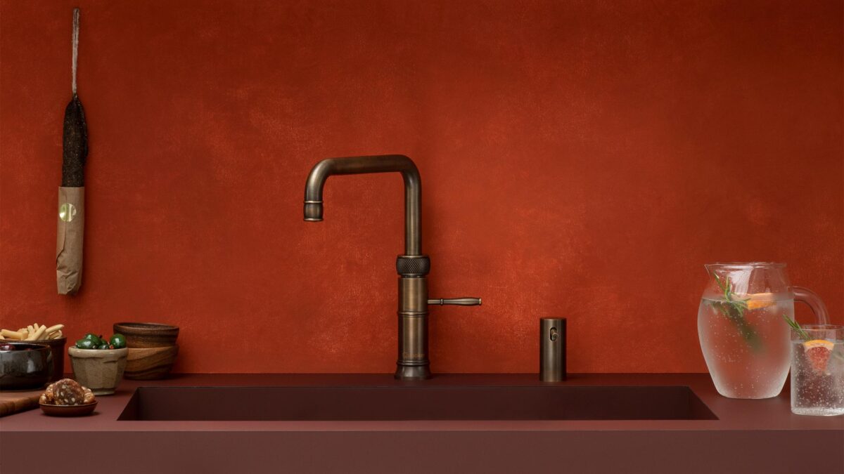 der quooker classic fusion in messing patina in einer roten küche