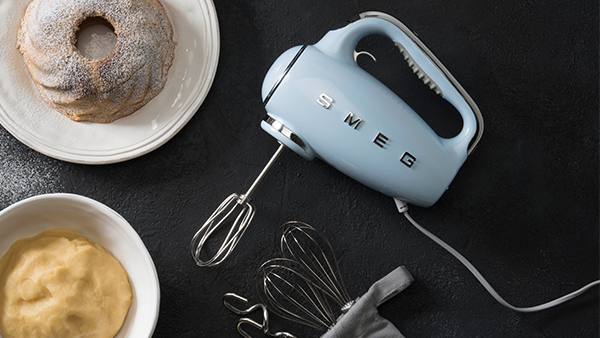 smeg handmixer in pastellblau und retro look auf schwarzem untergrund