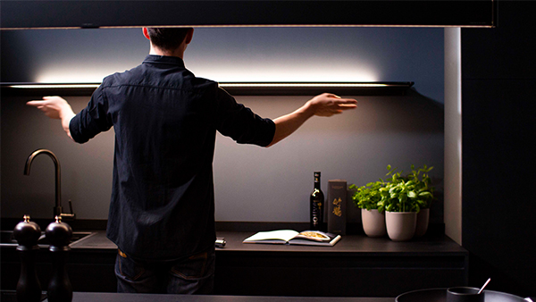 ein mann zeigt wie die novy gestensteuerung der küchenlampen funktioniert