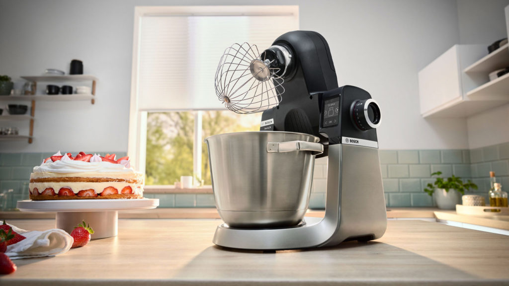 bosch serie 6 küchenmaschine mit schneebesen neben einer erdbeersahnetorte