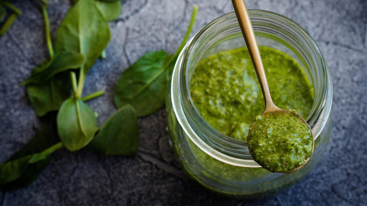 basilikumpesto auf einem löffel über einem glas