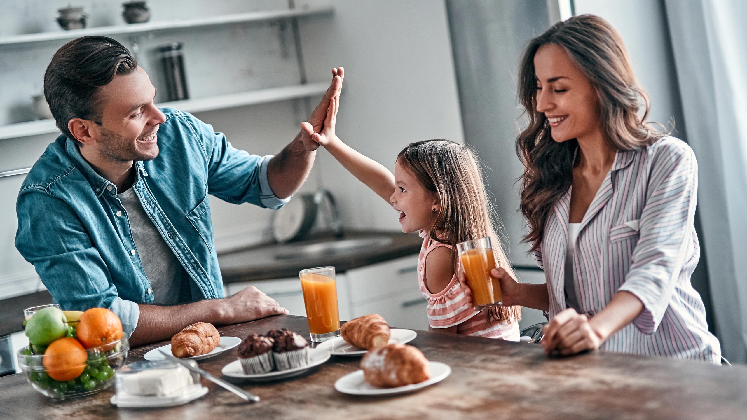 eine junge familie mit mädchen sitzt am frühstückstisch