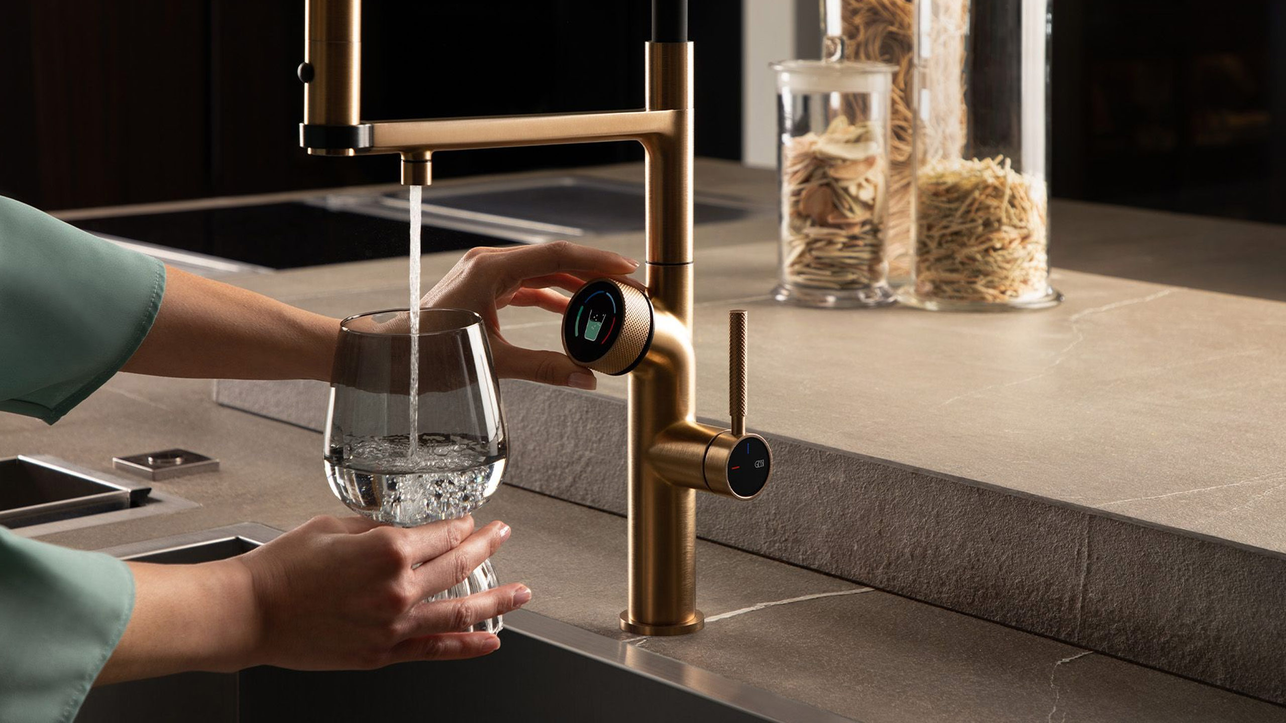 frau füllt wasser aus der gessi armatur in ein glas