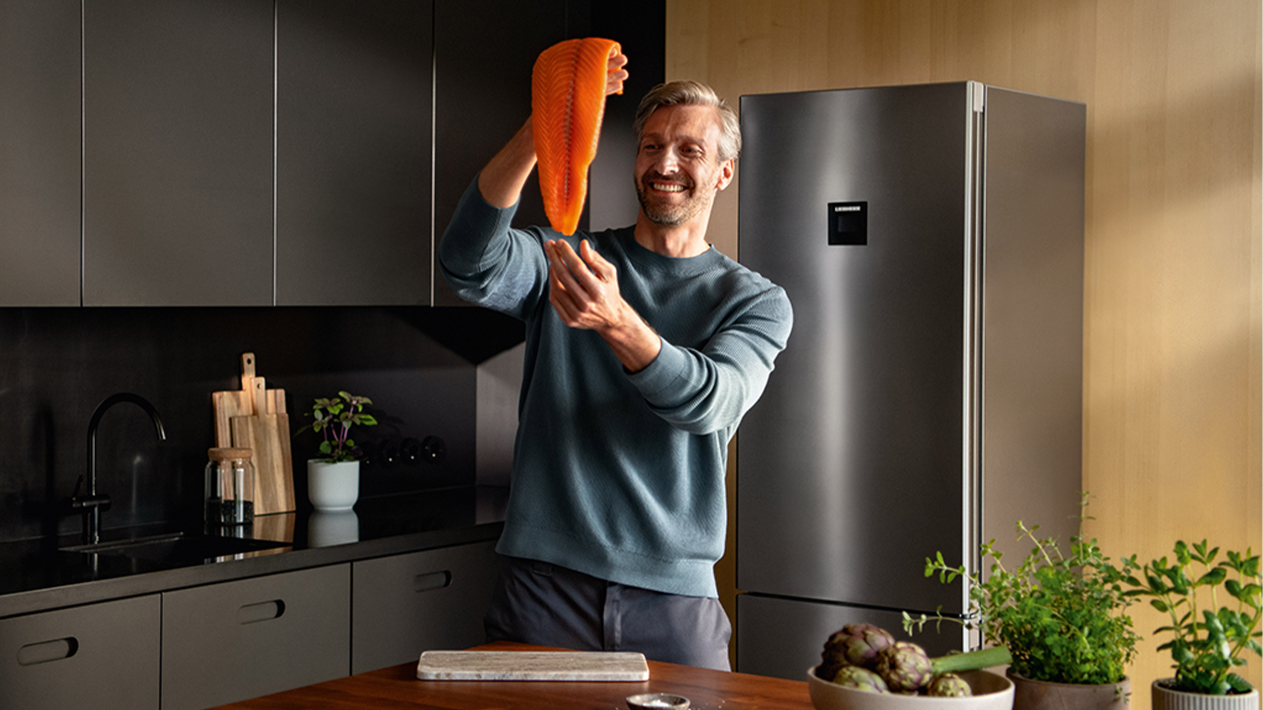 mann hält frischen lachs in einer küche mit liebherr kühlschrank