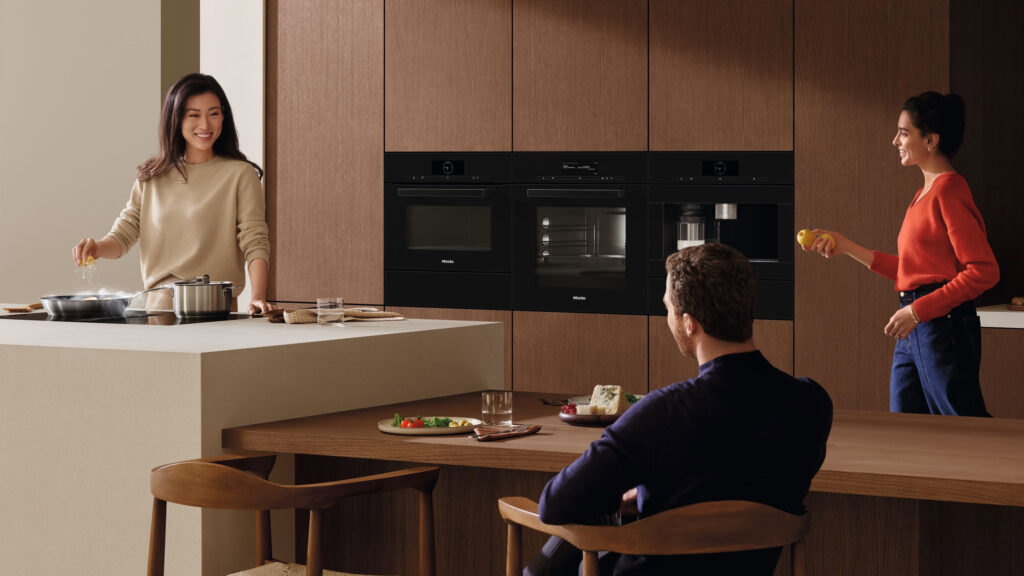 drei personen in einer modernen miele küche