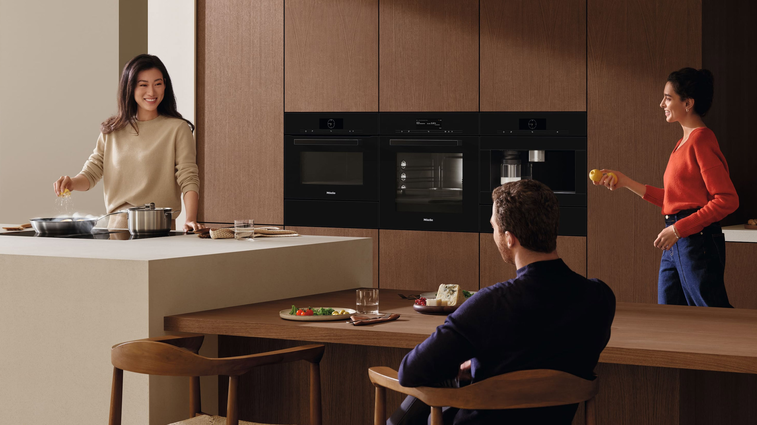 drei personen in einer modernen miele küche
