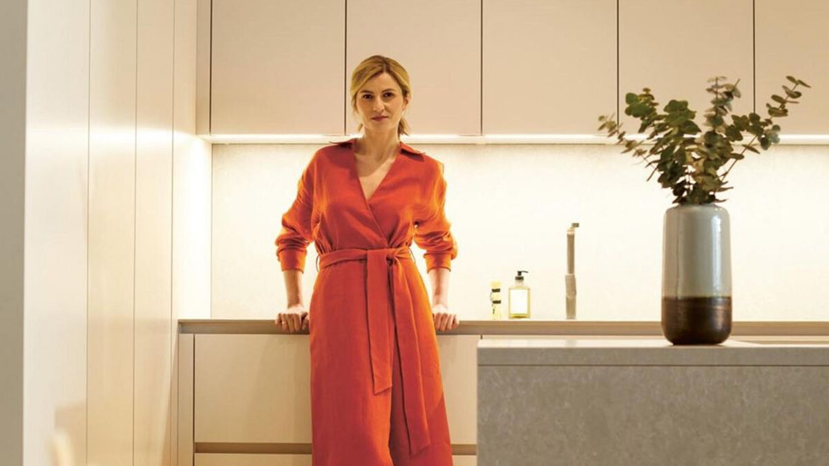 frau im orangenen kleid steht in einer next125 designküche