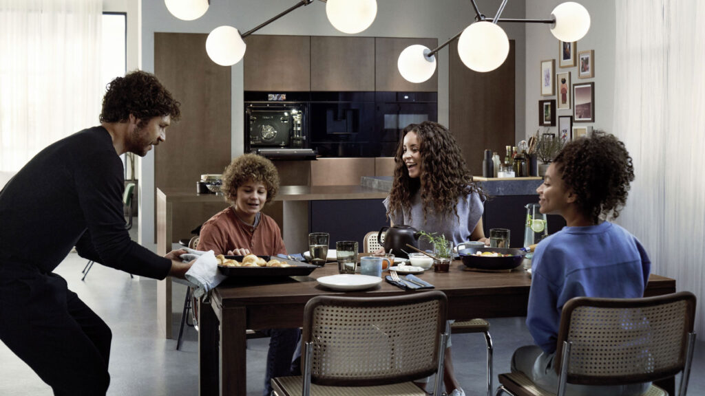 familie sitzt an einem esstisch in einer küche mit siemens küchengeräten