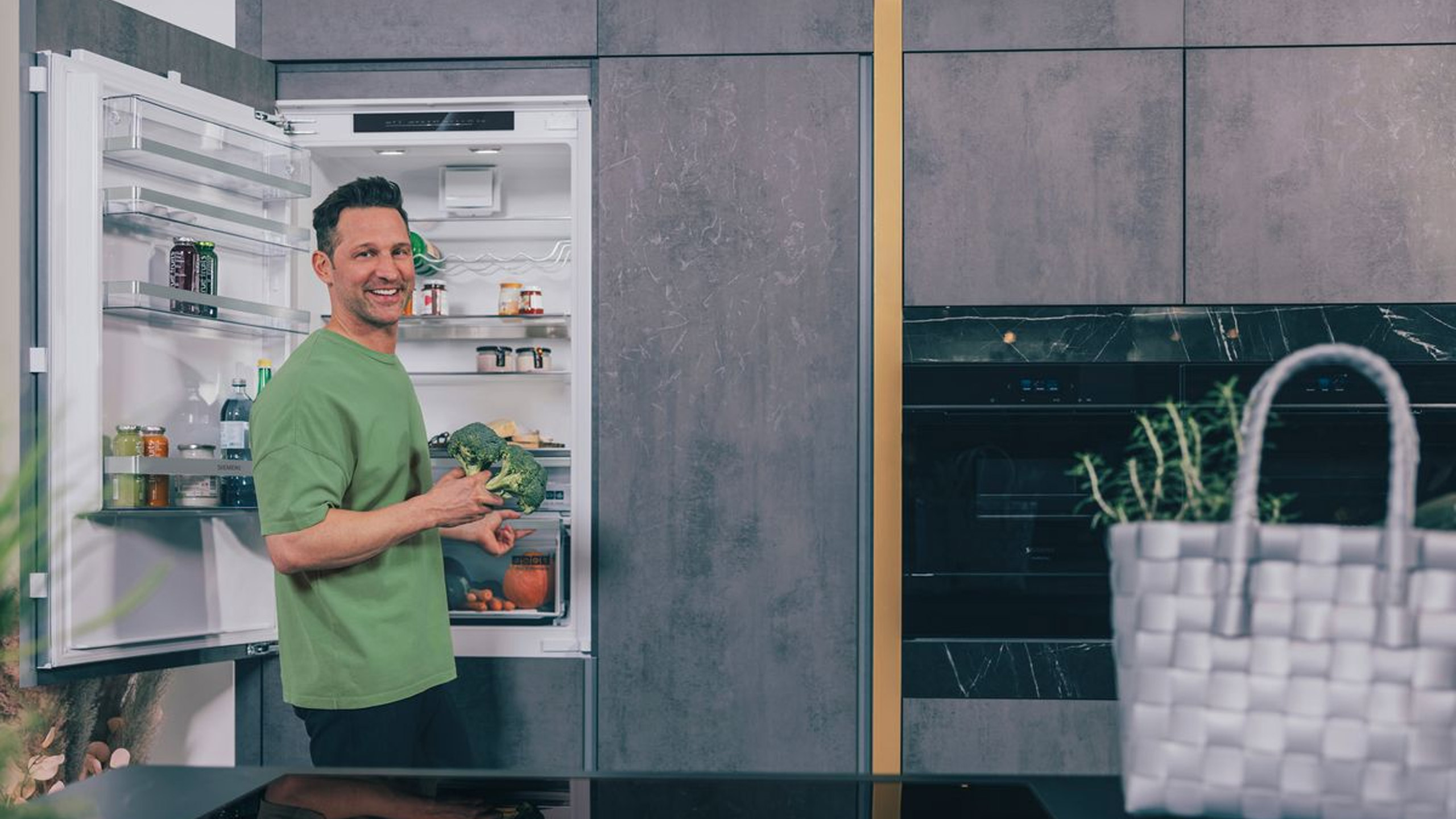 mann holt brokkoli aus einem siemens einbau-kühlschrank