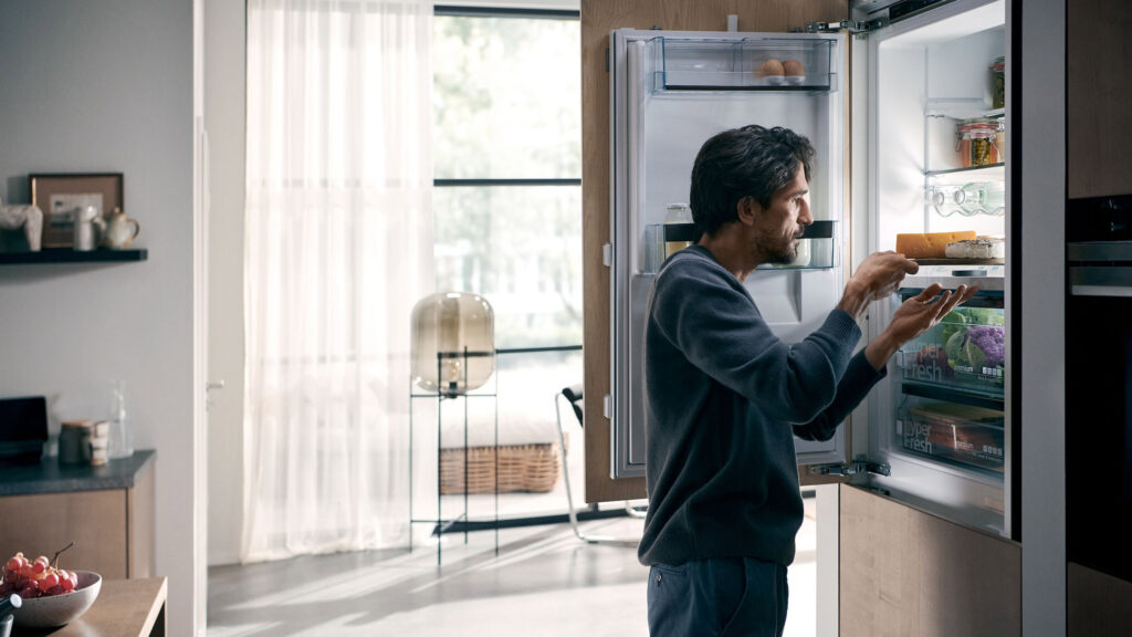 mann holt ein käse tablett aus einem siemens einbau-kühlschrank