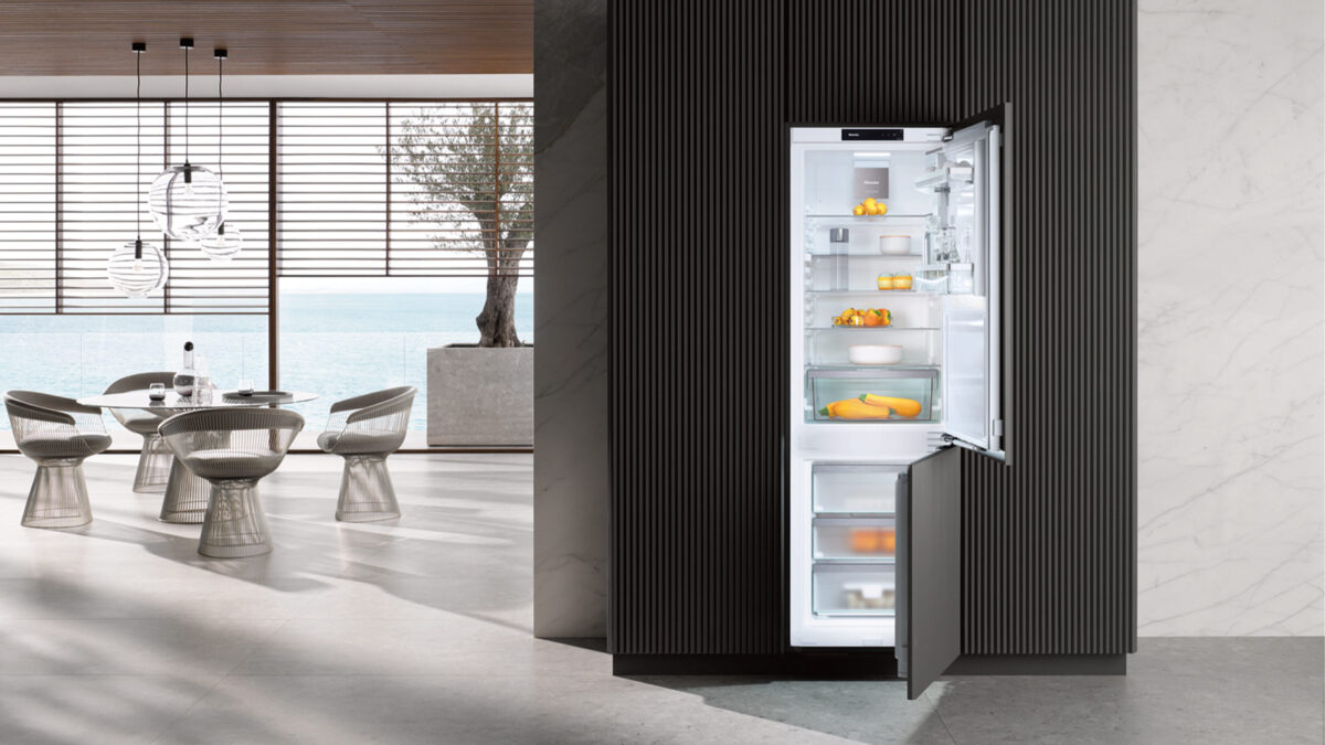 geöffnete miele kfn 7734 c kühl-gefrierkombination in einer küche mit rundem esstisch und meerblick