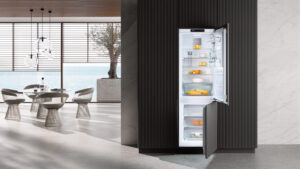 geöffnete miele kfn 7734 c kühl-gefrierkombination in einer küche mit rundem esstisch und meerblick