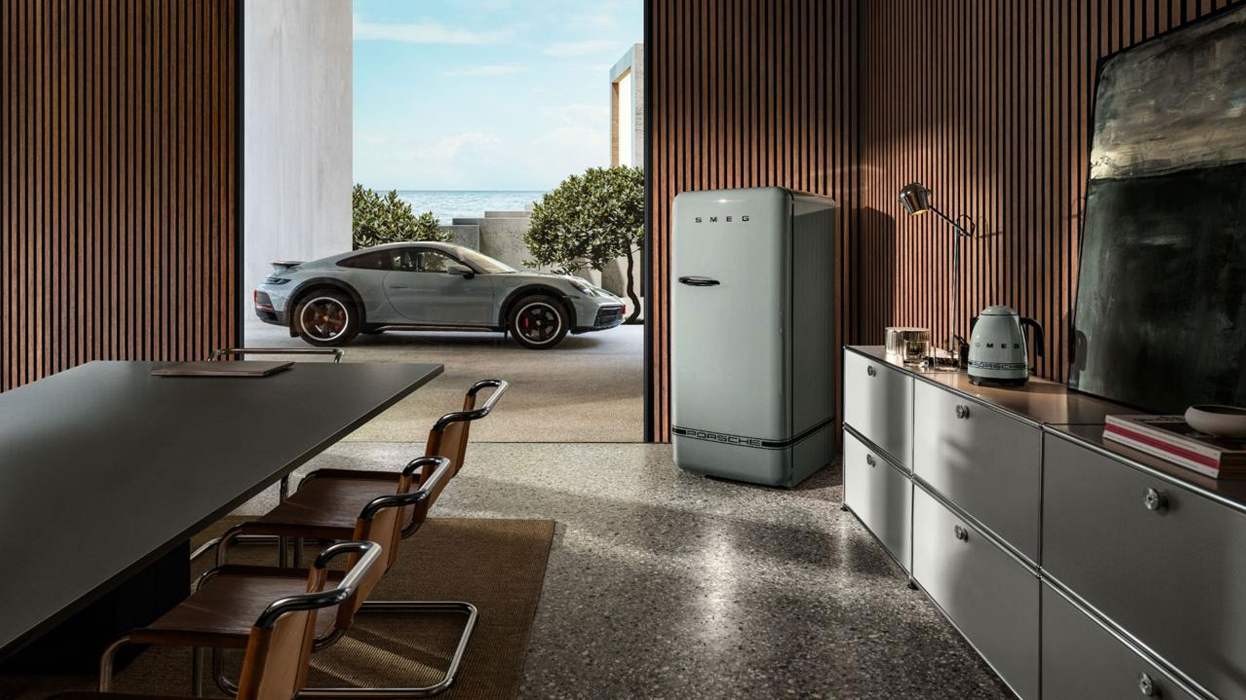 smeg porsche küchengeräte in einer küche mit glasfront vor der ein hellblau porsche steht